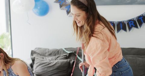 Family Cleaning After Celebration in Living Room with Balloons