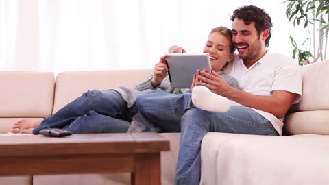 Young Couple Relaxing with Tablet on Cozy Sofa