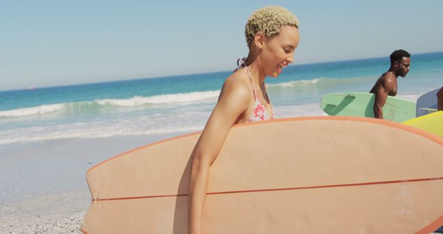 Young adults enjoying a sunny day at the beach while carrying their surfboards and smiling. Perfect for promoting summer activities, beach vacations, outdoor adventures, and surfing cultures.