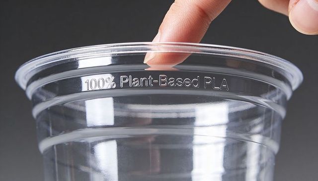 Fingertip touching rim of 100% plant-based pla cup showing compostable bioplastic detail