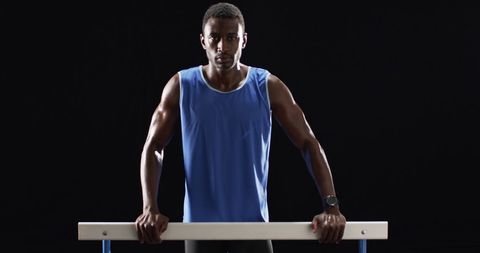Athlete in Blue Tank Top Gripping Parallel Bars with Intensity - Download Free Stock Images Pikwizard.com