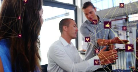 Discussing digital network strategy around laptop in bright office with network icons