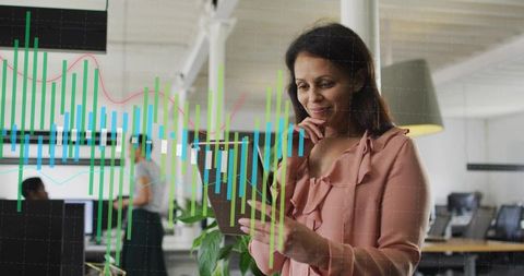 Businesswoman analyzing candlestick and trendline data on tablet in modern open office