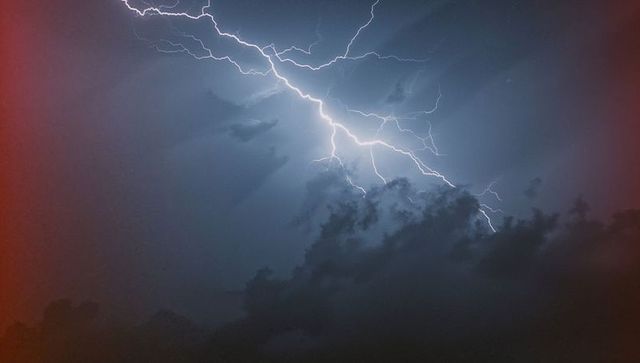 Dramatic Lightning Bolt Piercing Night Sky with Ominous Clouds