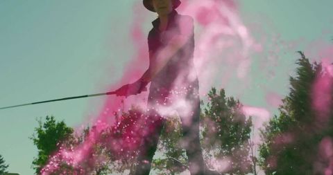 Senior Woman Swinging Golf Club Amidst Pink Powder on Sunny Day