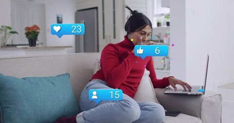 Sipping coffee while checking social media notifications on laptop in cozy living room
