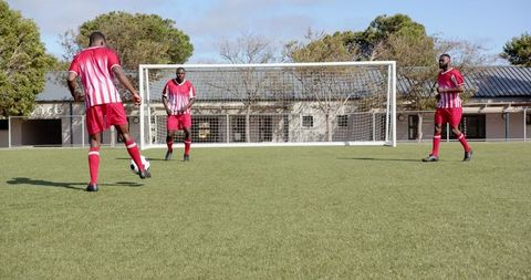 African american soccer team practicing passing drill on field
