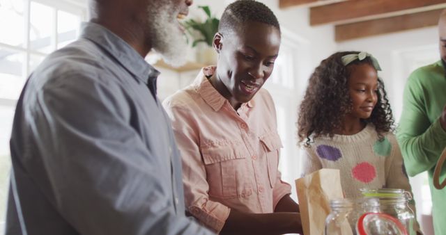 Image of happy african american parents with daughter and grandfather unpacking food shopping. Family, domestic life and togetherness concept digitally generated image.