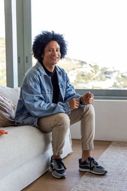 Smiling african american man sitting by window wearing denim jacket casual lifestyle