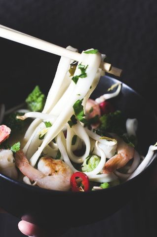 Chopstick grasping udon noodles with shrimp and vegetables