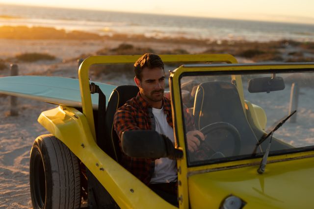 Caucasian man driving beach buggy on beach at sunset. beach stop off on summer holiday road trip.