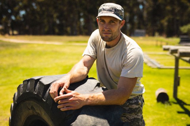 Portrait of caucasian mid adult male army soldier with tire during fitness boot camp training. unaltered, military recruit, military training, cross training, exercising and obstacle course.