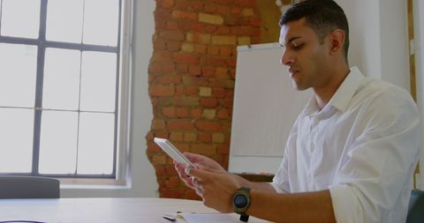 Focused Businessman Using Digital Tablet and Smartwatch in Modern Office