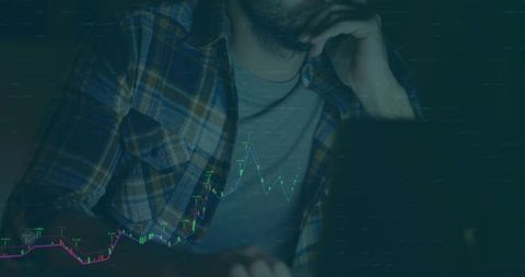 Man Analyzing Financial Trends on Laptop with Glowing Charts at Night