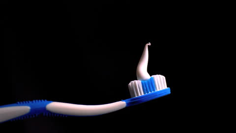 Toothpaste Curling on Toothbrush Over Dark Background
