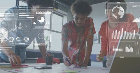 Young team brainstorming around table with laptop and digital data overlays for teamwork