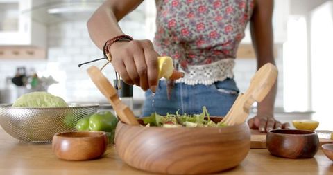 Young Woman Making Fresh Salad in Modern Kitchen