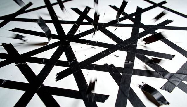 Revealing torn black duct tape grid creating abstract monochrome texture with shadows
