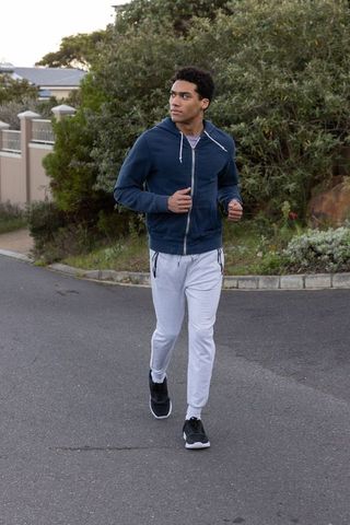 Man jogging through suburban neighborhood in urban attire