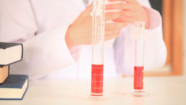 Female scientist pouring red liquid from one beaker to another one in a laboratory. This video can be used for educational content, scientific research materials, laboratory procedures guides, or chemistry publications.