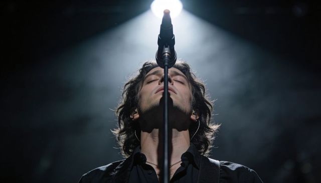 Male rock vocalist performing under spotlight with microphone stand and smoky stage