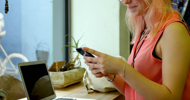 Young Woman Texting on Smartphone While Working on Laptop - Download Free Stock Images Pikwizard.com