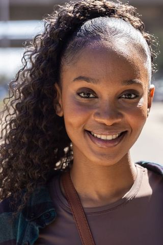 Smiling african american woman outdoors wearing green plaid shirt and crossbody bag