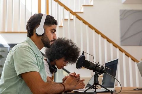 Diverse podcasters recording episode with microphones and laptops