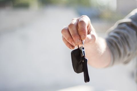 Hand holding car keys on blurred background