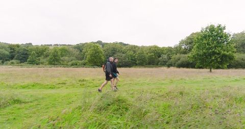 People strolling through lush green fields on an overcast day
