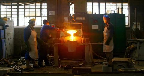 Industrial workers performing metal pouring in foundry