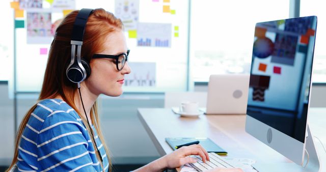 Young Professional Woman Wearing Headphones Working on Computer - Download Free Stock Images Pikwizard.com