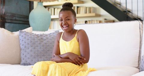 Joyful Young Girl Sitting on Couch in Bright Room