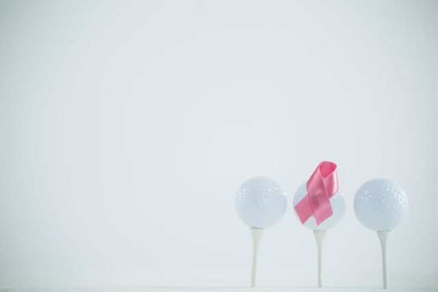 Pink Breast Cancer Awareness ribbon on golf ball against white background