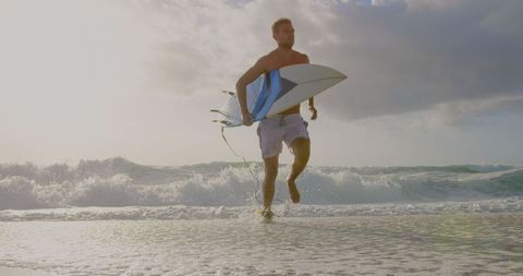 Energetic Surfer Running on Beach with Surfboard