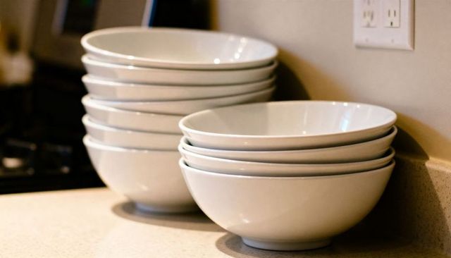 Stacking white ceramic bowls on kitchen countertop with warm ambient light