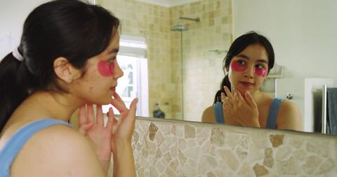 woman using skincare hydrogel patches in bathroom reflecting - Download Free Stock Images Pikwizard.com