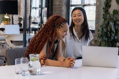 Diverse Female Coworkers Collaborating on Laptop in Modern Office