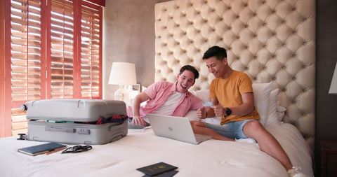 Joyful male couple planning their exciting vacation together