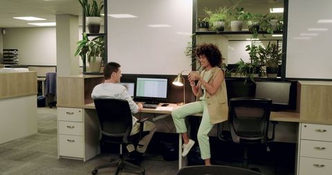 Colleagues engaging in discussion near office workstation