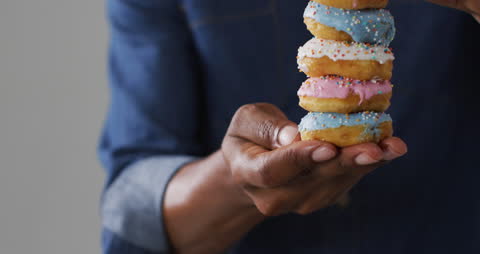 Person Holding Stack of Colorful Frosted Donuts