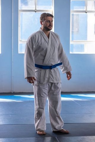 Martial arts student in white gi practicing in bright dojo