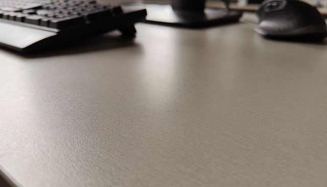 Light textured laminate desk surface with black keyboard and ergonomic mouse workspace