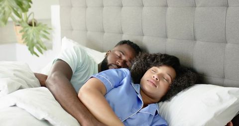 African American couple spooning peacefully in bed wearing blue pajamas cozy minimalist bedroom