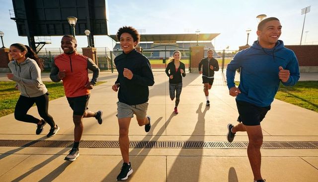 Diverse group running together at stadium during golden hour teamwork and fitness