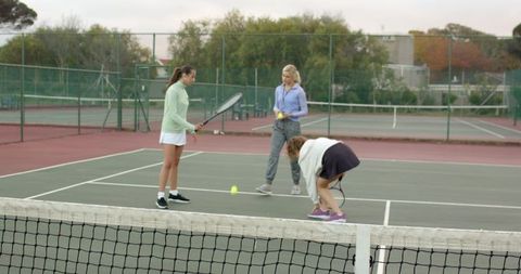 Women practicing tennis drills on outdoor court during coaching session at club facility