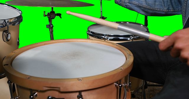 Hands on drummer playing drum against green screen