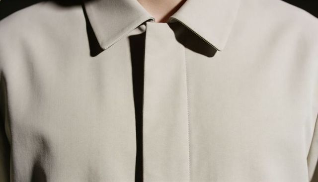Minimal beige coat closeup showing hidden placket, clean collar and tailored seams