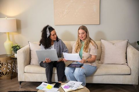Diverse female colleagues collaborating on sofa in cozy home setting