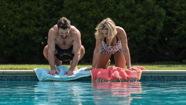 Couple leaning over pool pressing palms on towels backyard swimwear lifestyle fitness